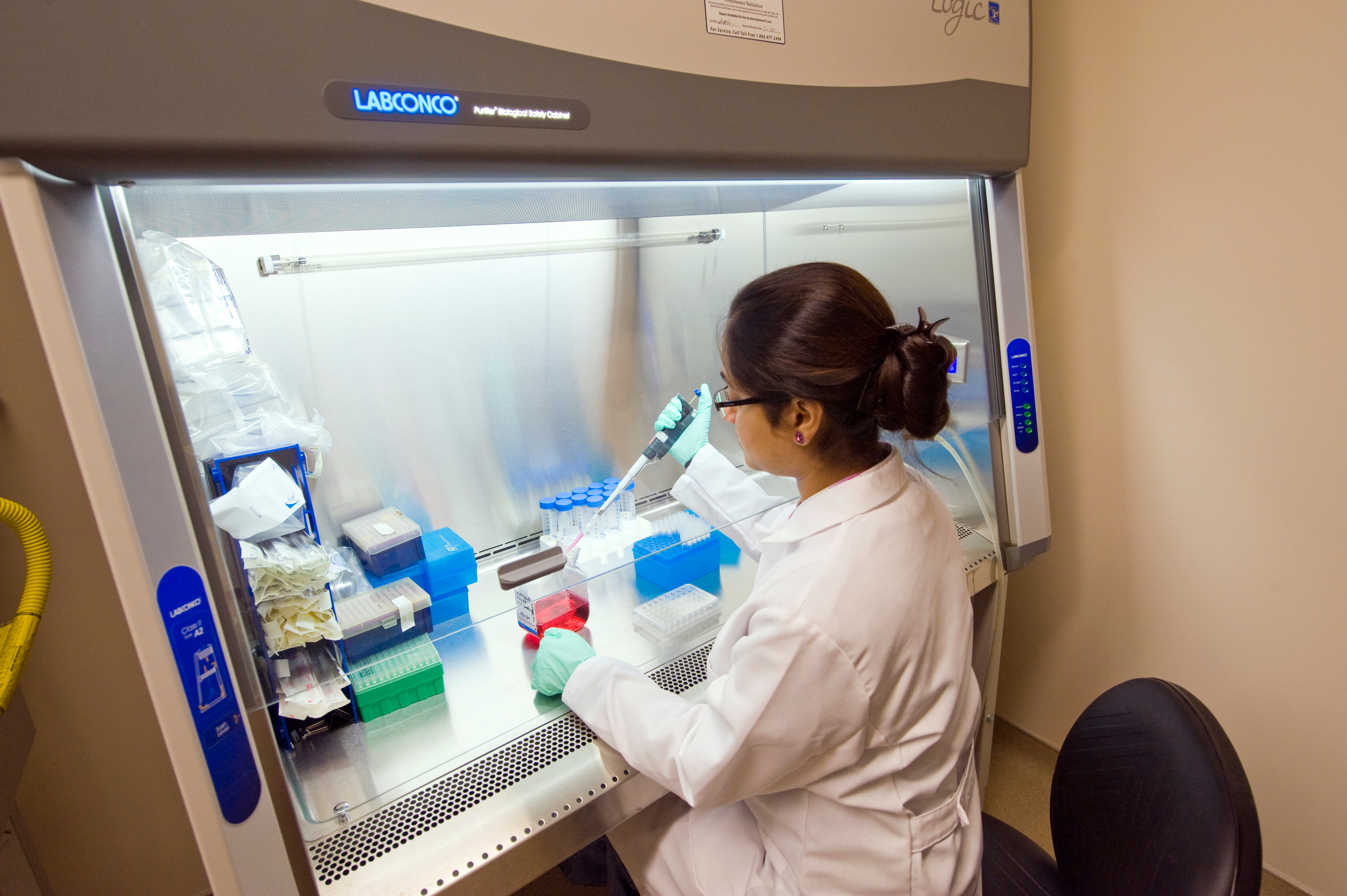 a scientist adds lab samples to a refrigerator unit